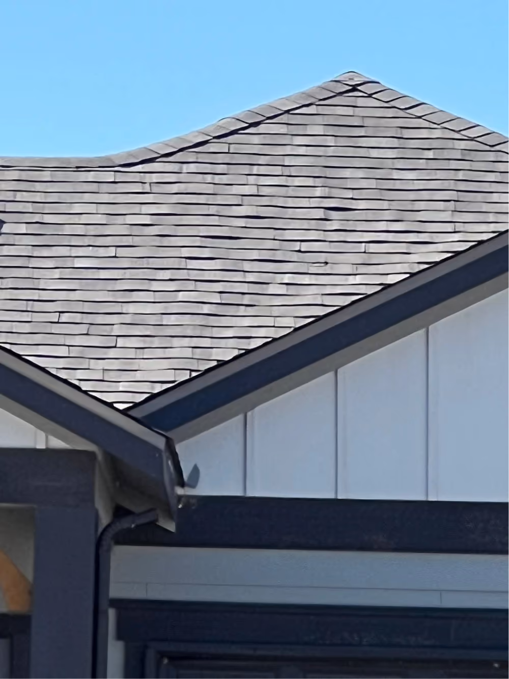 Gray shingles along the roof edge above a gutter