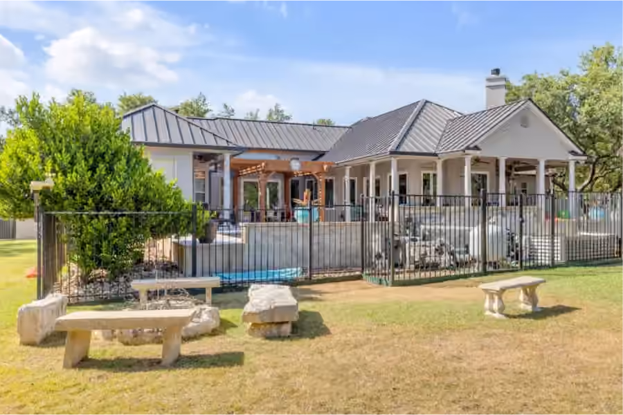 Home with a standing-seam metal roof, covered patio and fenced pool